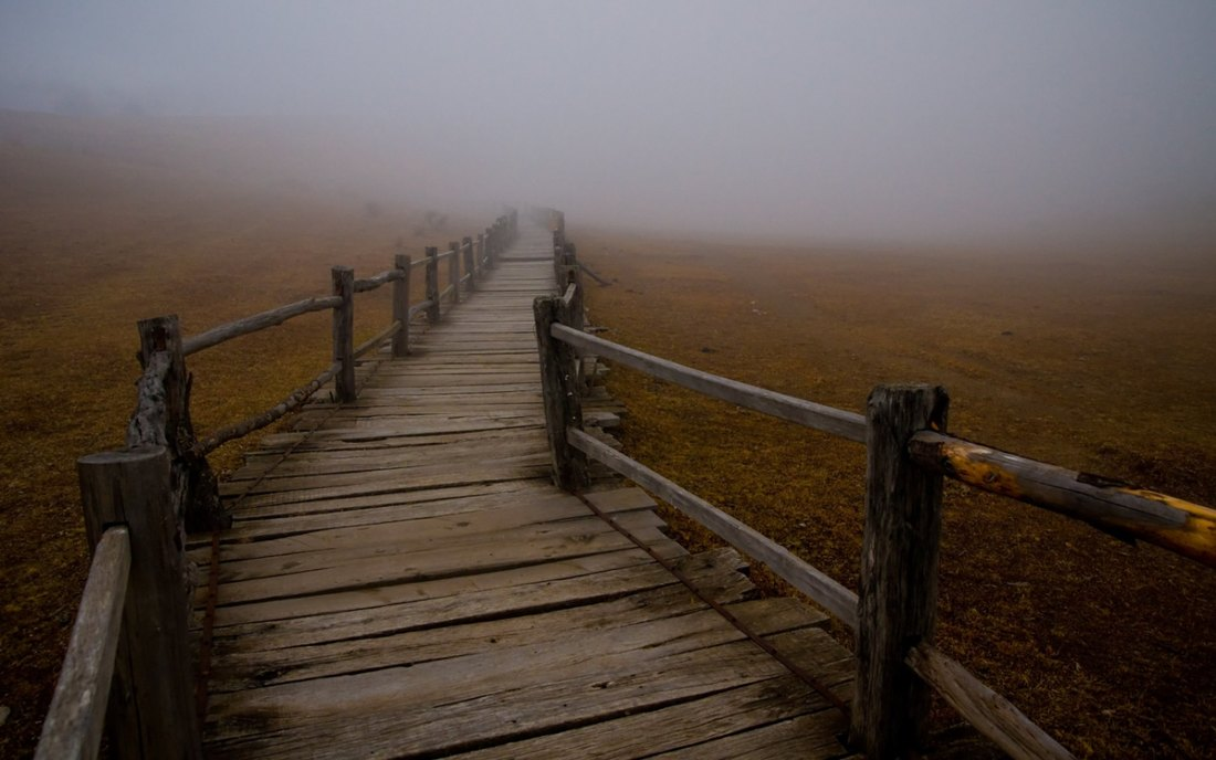 Winding Bridge leading into deep fog.